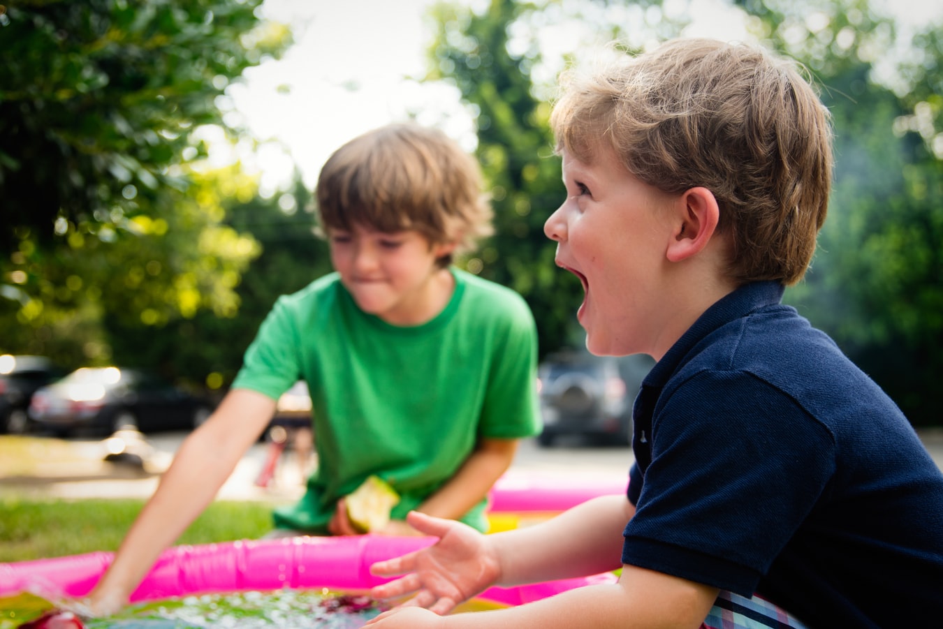 two young boys playing with water outside